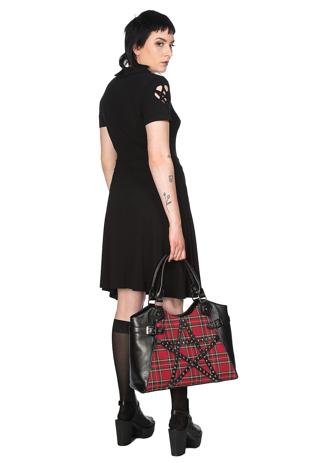 Alternative model holding a red tartan handbag with studded pentagram feature.