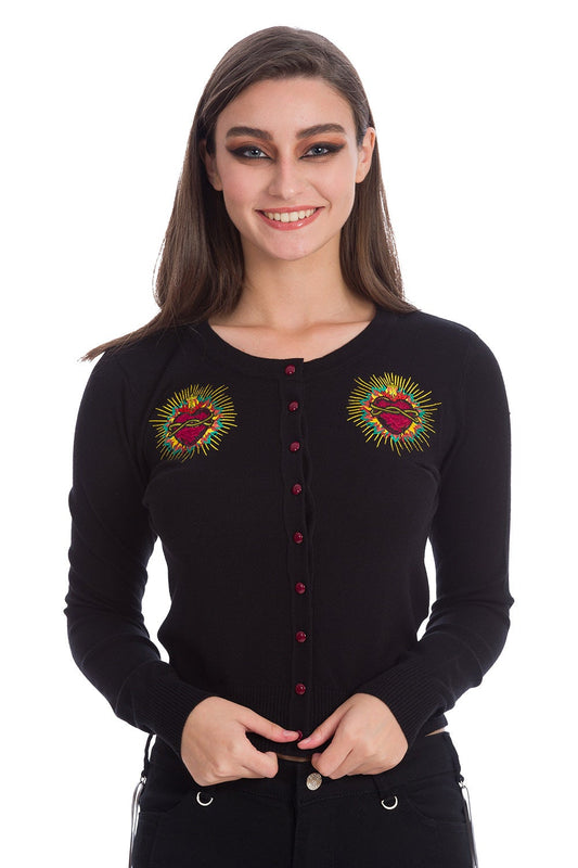 Model wearing black button up cardigan with embroidered red heart on either chest and red buttons.