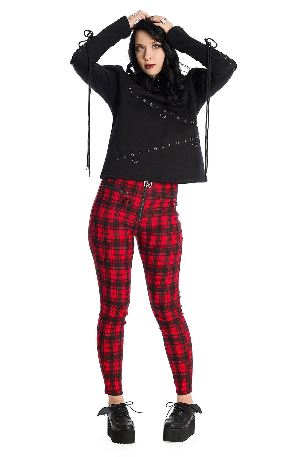 Alternative model wearing high waisted red check trousers with pentagram zip details.