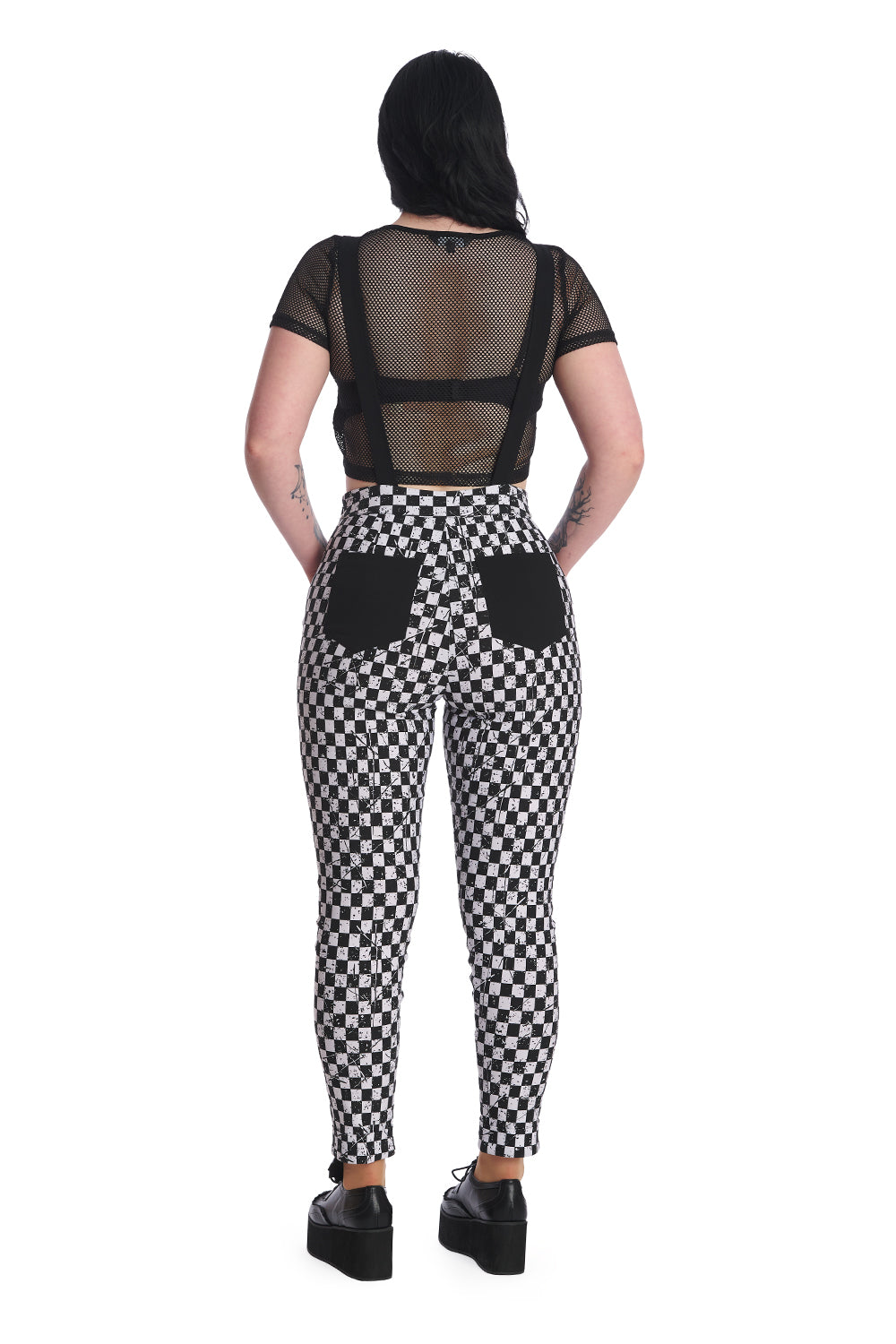 Alternative model wears black and white checkerboard dungarees with black mesh crop top underneath.