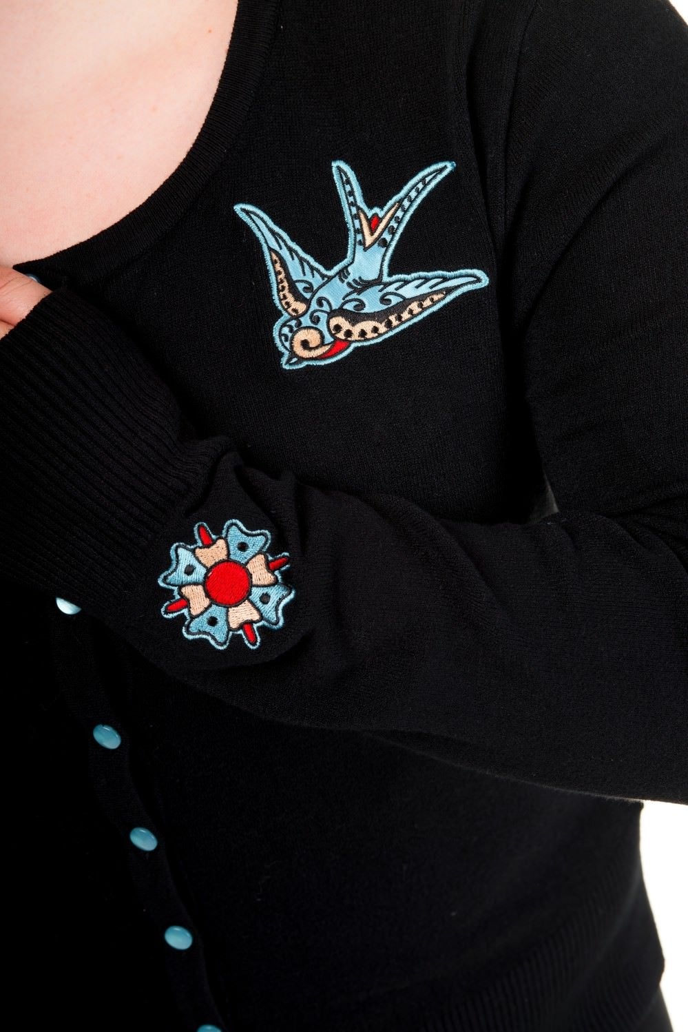Model wearing black button up cardigan with blue buttons and blue swallow chest pieces and wrist detail
