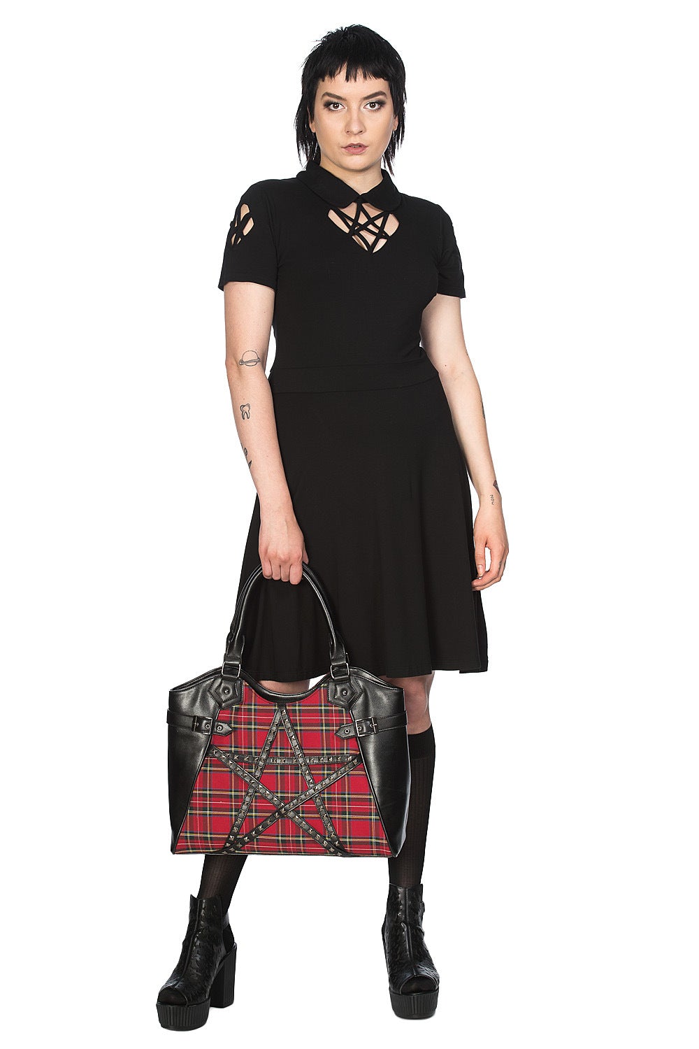 Alternative model holding a red tartan handbag with studded pentagram feature.