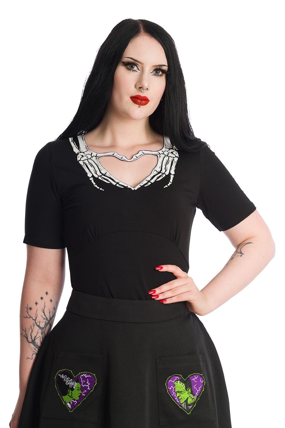 Alternative model wears short sleeve black top with skeleton hands around the collar creating a heart shape. 