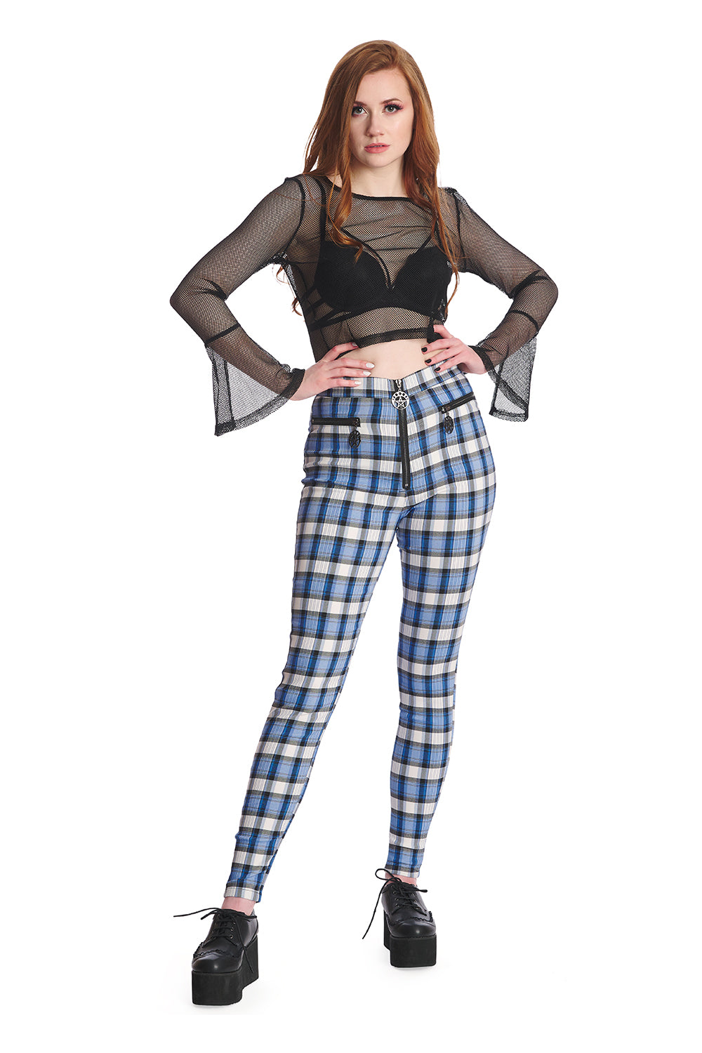 Alternative model in black mesh crop top with blue and white checked high waisted skinny legged trousers.