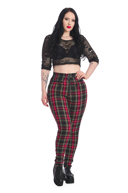 Alternative model in black skull mesh crop top with red tartan skinny legged, high waisted trousers.