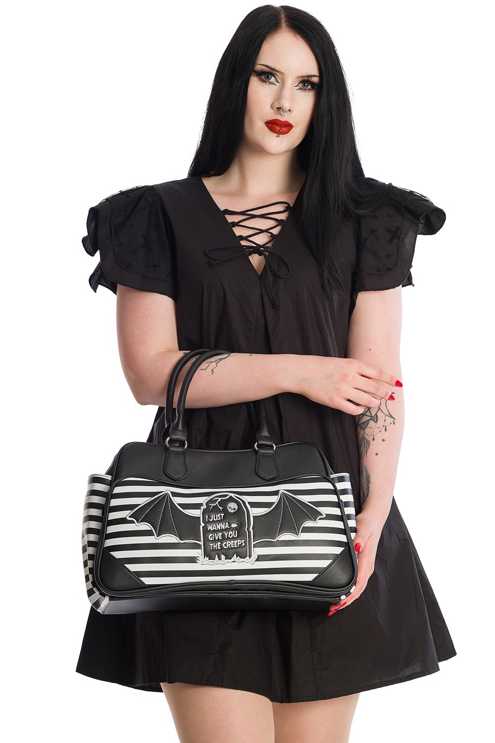 Model holding large black handbag in black and white stripe with gravestone and batwing print with the phrase 'I just wanna give you the creeps' 