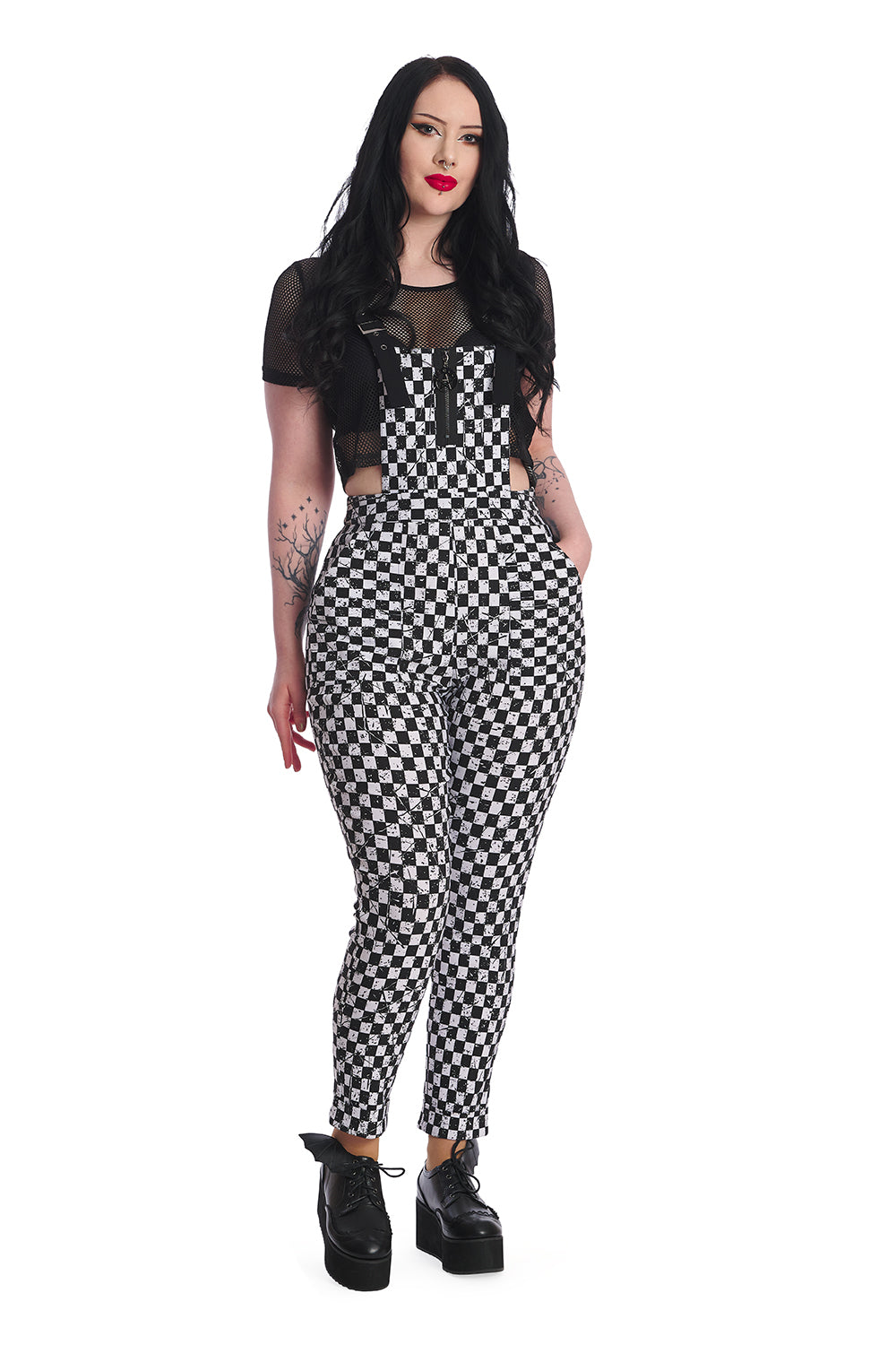Alternative model wears black and white checkerboard dungarees with black mesh crop top underneath. 